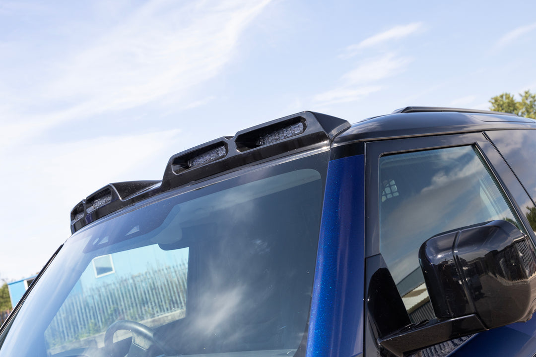 Black roof-mounted LED light bars installed on the roof of a blue vehicle, photographed outdoors against a blue sky.