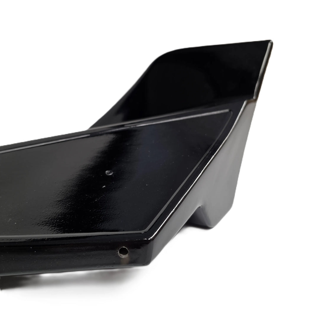 A close up shot of the reverse end of a rear bumper canard finished in a glossy black