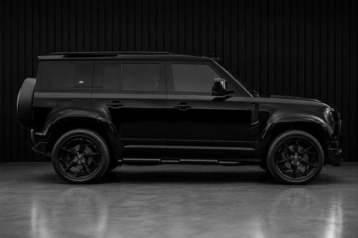A black SUV shown in full side profile against a dark studio backdrop with a reflective floor.
