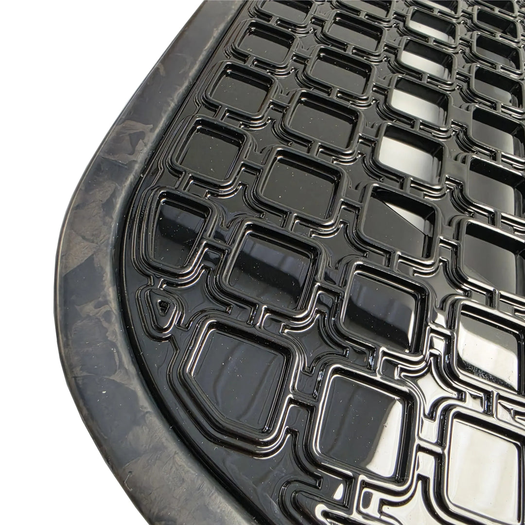Close Up Shot of a black car side vents with forged carbon surrounds with gloss black grid pattern on a white background