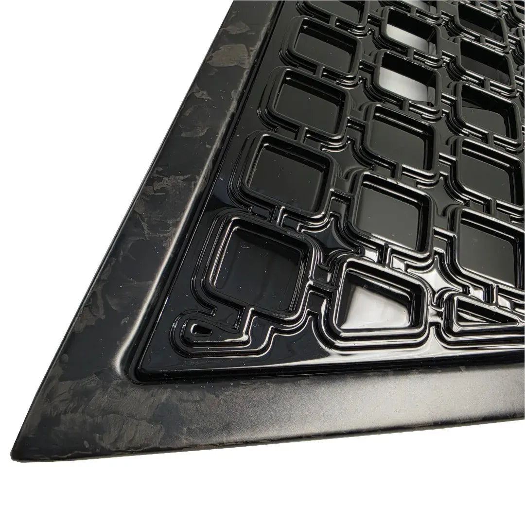 Close up Shot of corner of a black car side vents with forged carbon surrounds with gloss black grid pattern on a white background