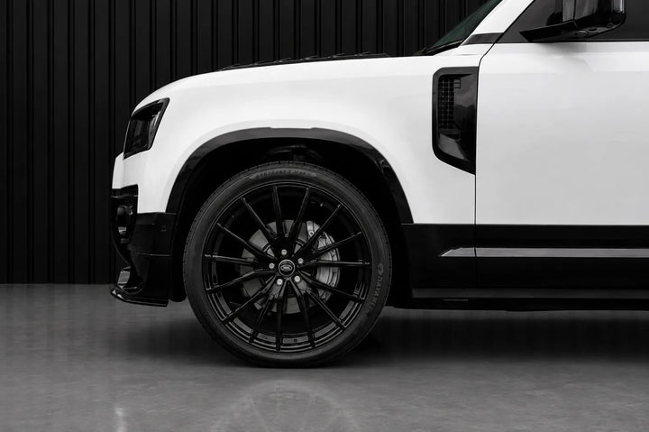 A close-up side view of a white SUV with black wheels, black trim, and a black background.