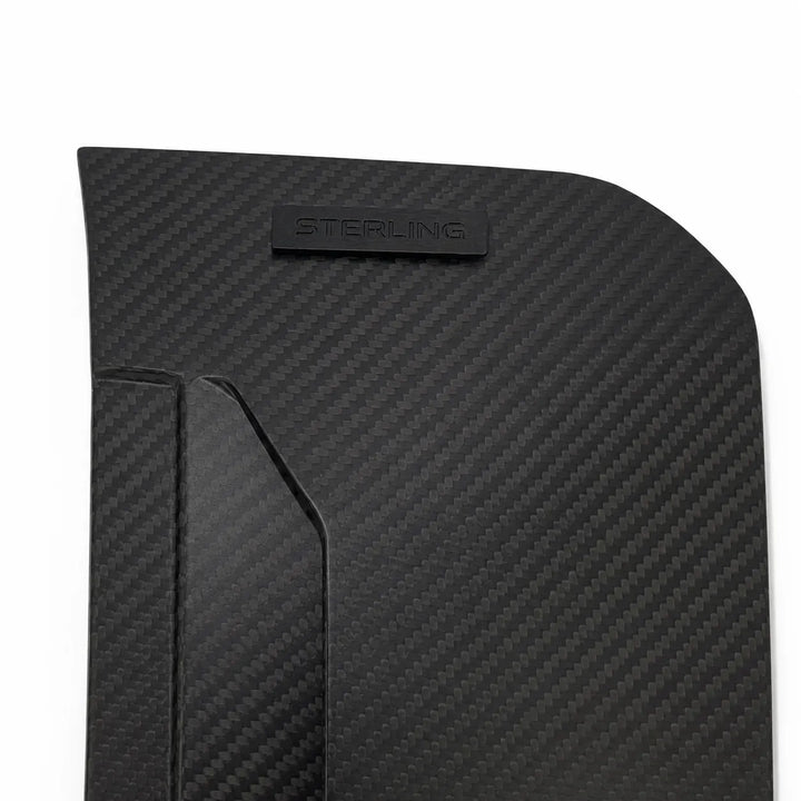 A close-up of a black carbon fiber textured panel with a small embossed 'STERLING' logo, shown on a white background.