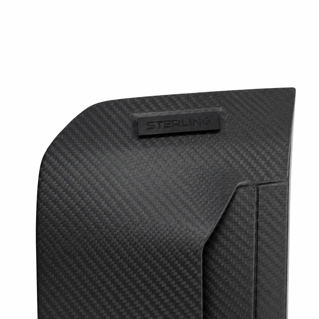 Close-up of a black carbon fiber textured product surface with a small embossed STERLING logo plaque, shown on a white background.