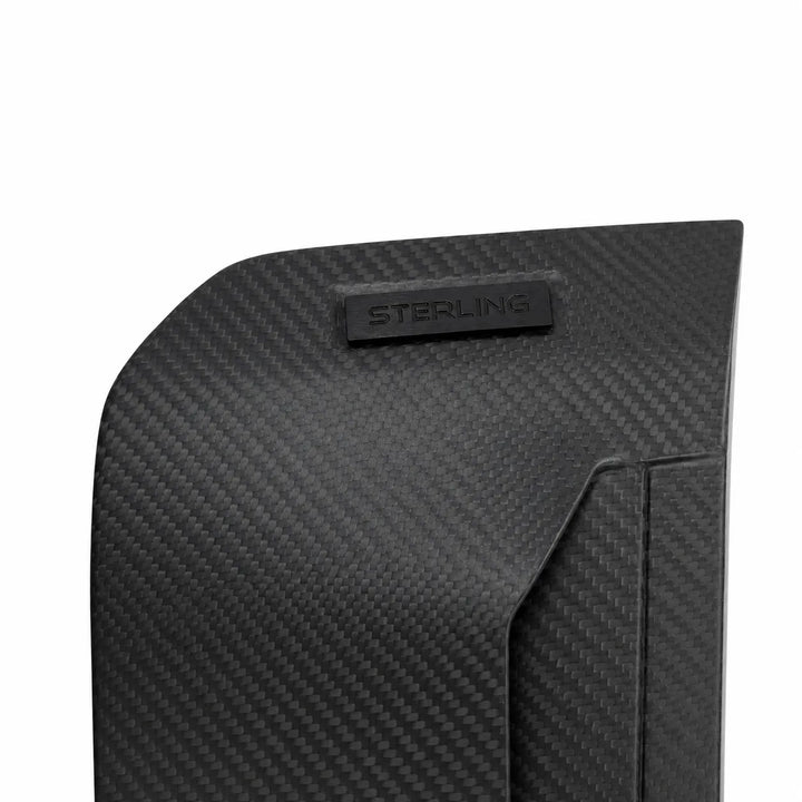 Close-up of a black carbon fiber textured product surface with a small embossed STERLING logo plaque, shown on a white background.