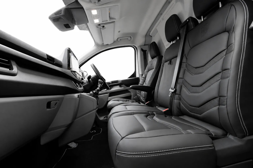 Black leather front passenger seat and matching rear seats in a van, shown from an interior side-angle view with the dashboard and driver's side visible.