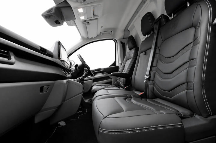 Black leather front passenger seat and matching rear seats in a van, shown from an interior side-angle view with the dashboard and driver's side visible.