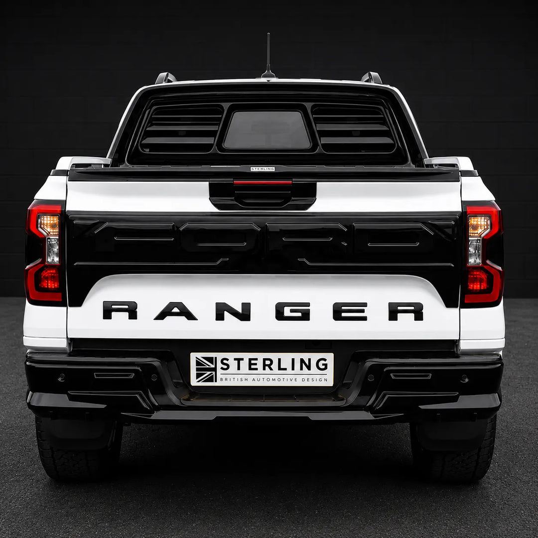 Rear view of a white and black Ford Ranger pickup truck with a black rear window tint and a license plate frame reading 'STERLING BRITISH AUTOMOTIVE DESIGN'.