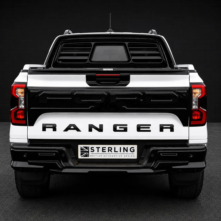 Rear view of a white and black Ford Ranger pickup truck with a black rear window tint and a license plate frame reading 'STERLING BRITISH AUTOMOTIVE DESIGN'.