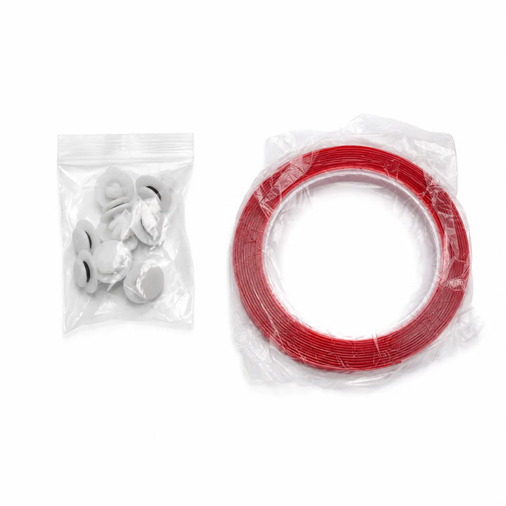 A set of small hardware accessories on a white background, including a clear plastic bag with several white plastic fasteners or grommet-like pieces on the left, and a larger clear plastic-wrapped roll of red tape or cord on the right.