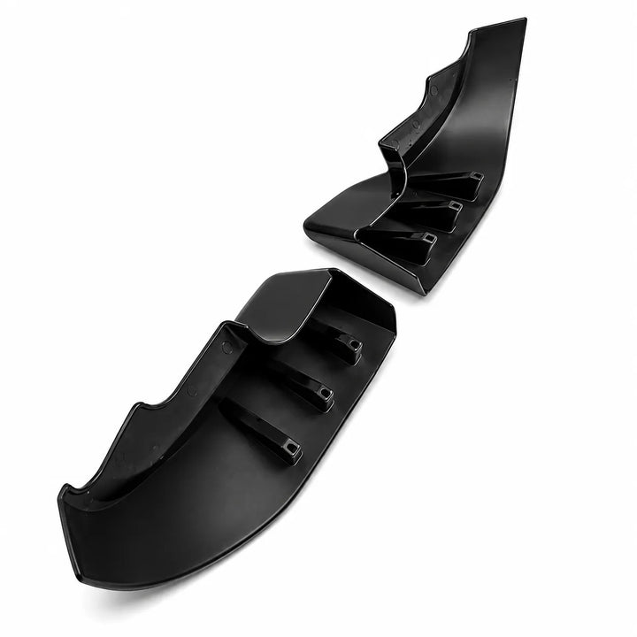 A high up shot of a pair of glossy black plastic automotive trim pieces, lower bumper lip fender extension, shown against a plain white background.