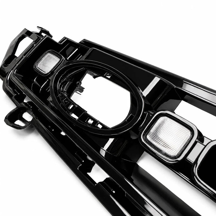 A glossy black plastic automotive bumper grille trim piece with integrated light housings LED Lights, photographed on a clean white background.

