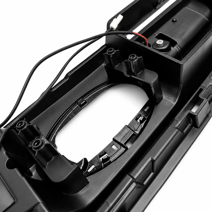 Close-up of a black plastic automotive light housing or dashboard component with visible wiring and mounting tabs on a white background.