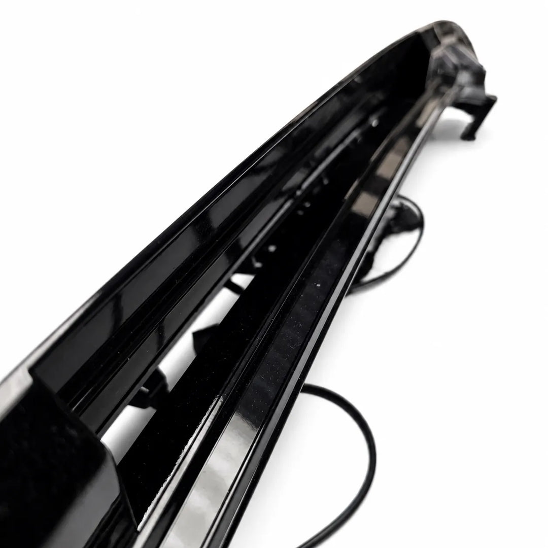 A glossy black car bumper trim piece with integrated mounting brackets and a black cable, shown on a plain white background.