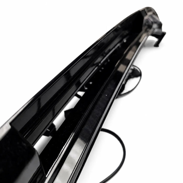 A glossy black car bumper trim piece with integrated mounting brackets and a black cable, shown on a plain white background.