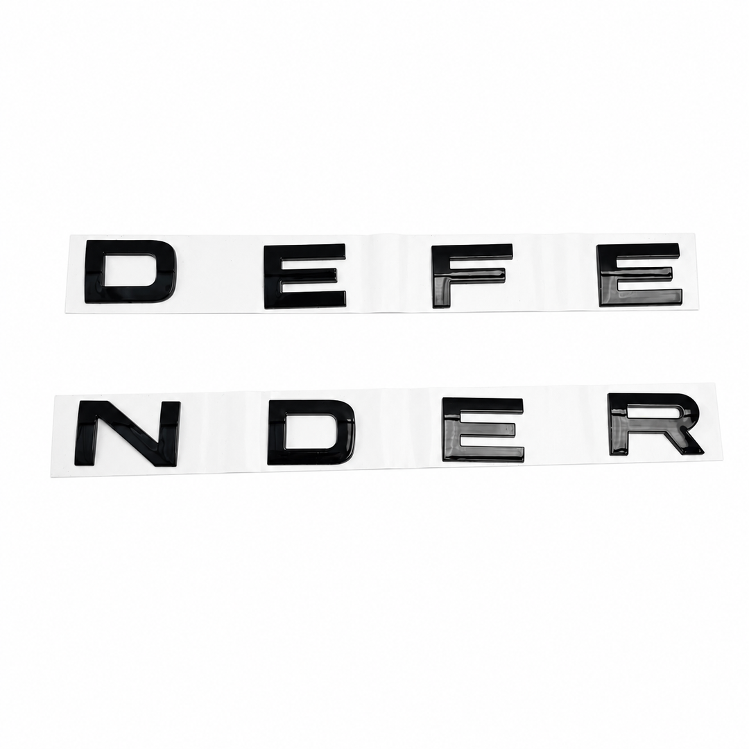 A pair of black raised letter decals spelling 'DEFENDER' across two white strips, shown on a plain white background.