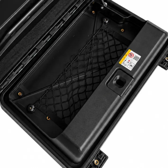 Close-up of the interior storage compartment of a black hard case, showing a black mesh storage net, molded plastic walls, and a small warning label on the right side.