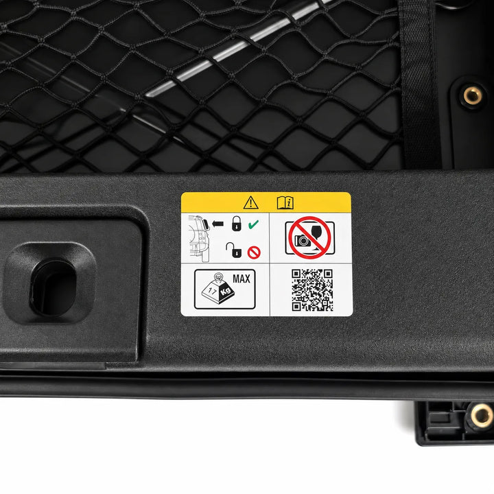 A close-up of a black metal equipment panel with a white and yellow safety instruction sticker showing icons, a QR code, and a maximum weight mark.