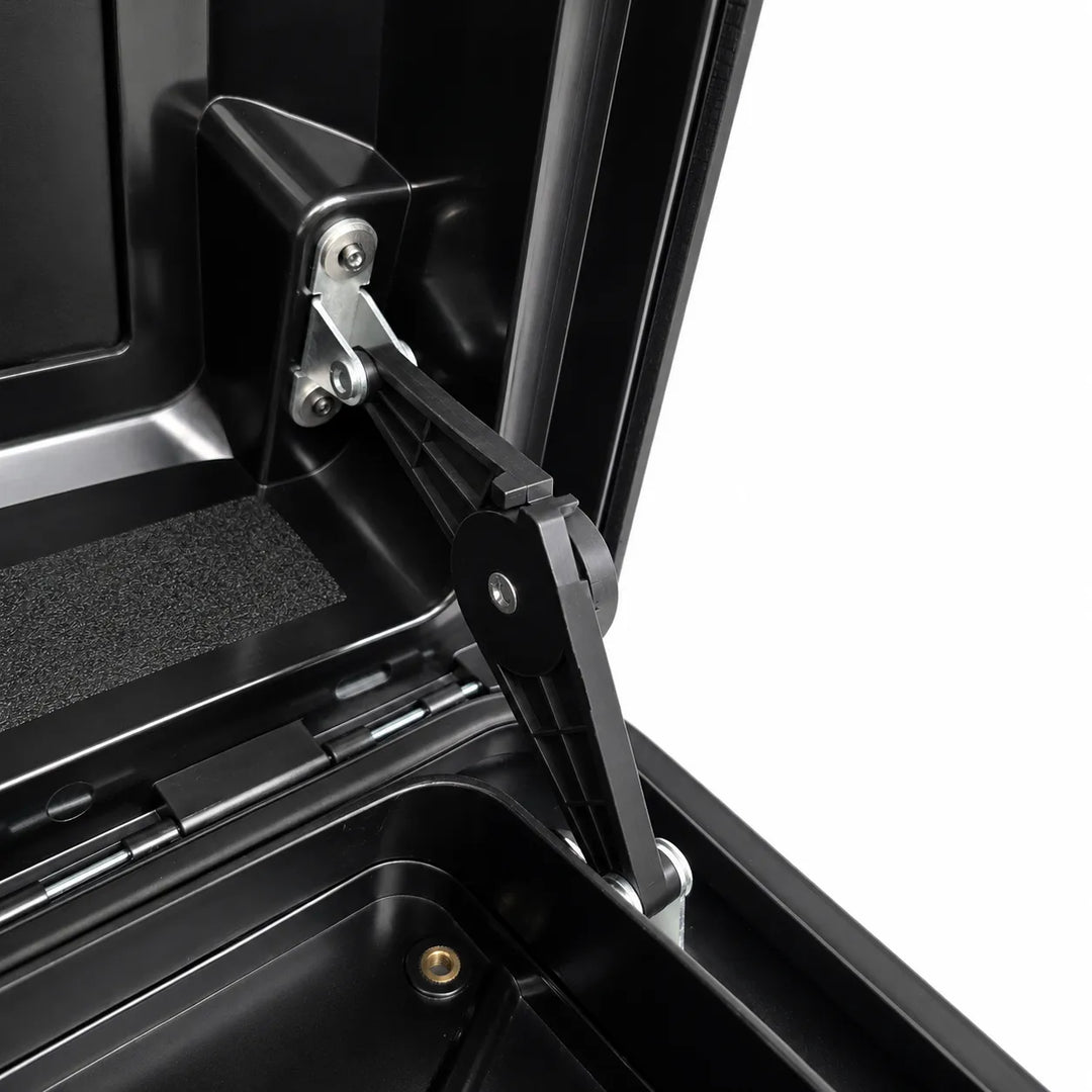 Close-up of a black hard-sided storage box or trunk lid hinge mechanism with metal fasteners, shown open against a white background.