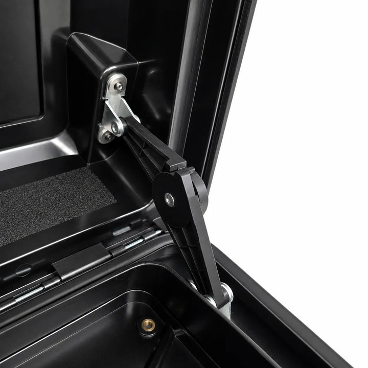 Close-up of a black hard-sided storage box or trunk lid hinge mechanism with metal fasteners, shown open against a white background.