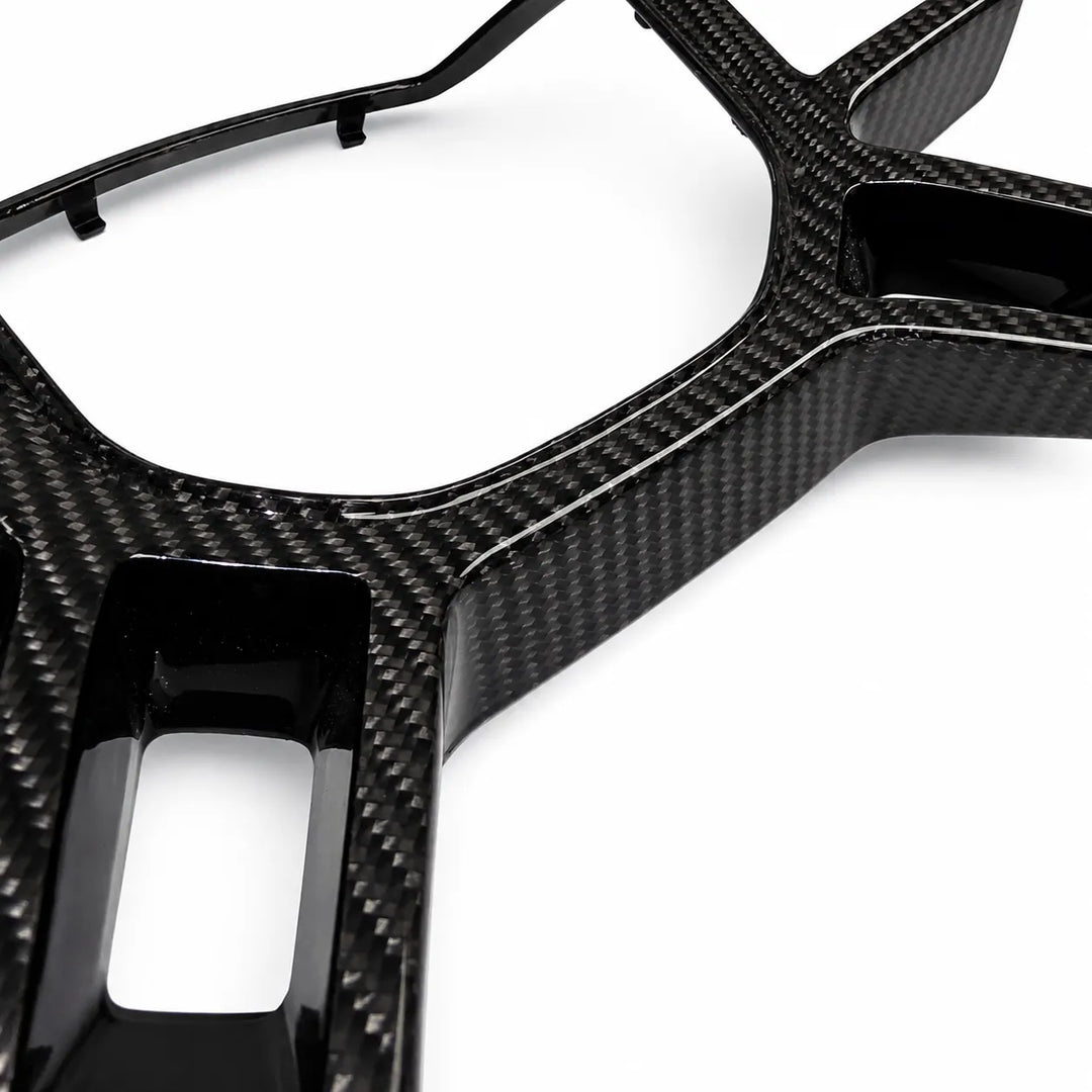 A close-up of a glossy black carbon fiber trim piece with a visible carbon weave pattern, shown on a clean white background.