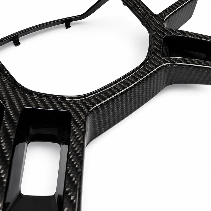 A close-up of a glossy black carbon fiber trim piece with a visible carbon weave pattern, shown on a clean white background.