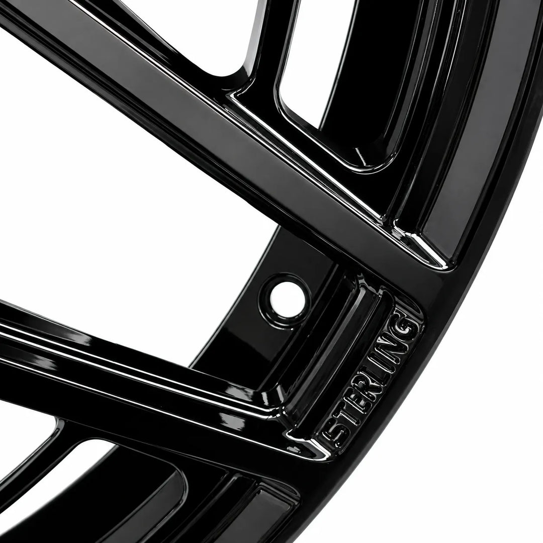 Close-up of a glossy black multi-spoke wheel rim with the brand name 'STERLING' embossed on the hub, set against a solid white background.