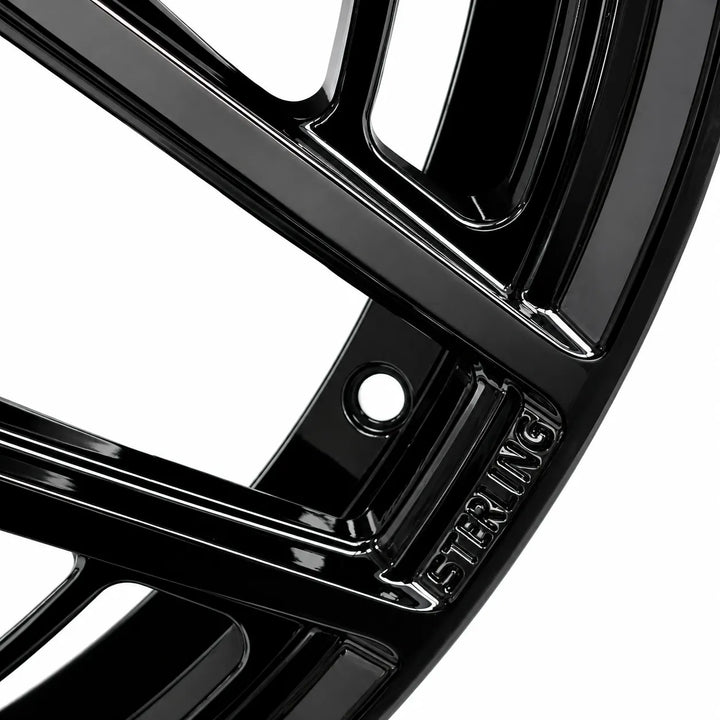 Close-up of a glossy black multi-spoke wheel rim with the brand name 'STERLING' embossed on the hub, set against a solid white background.