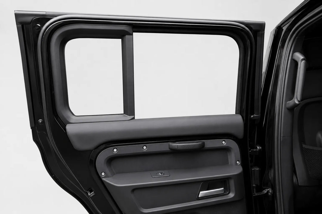 Close-up of a black vehicle door panel with the door open, showing the window frame, door handle area, and interior trim against a light gray studio background.