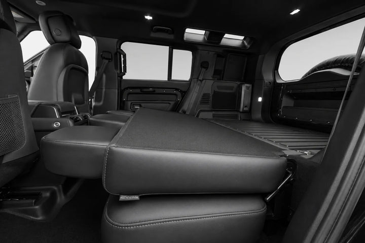 Black leather seats inside a vehicle, with the front passenger seat folded down to create a flat bed or cargo space, shown in a clean interior shot.