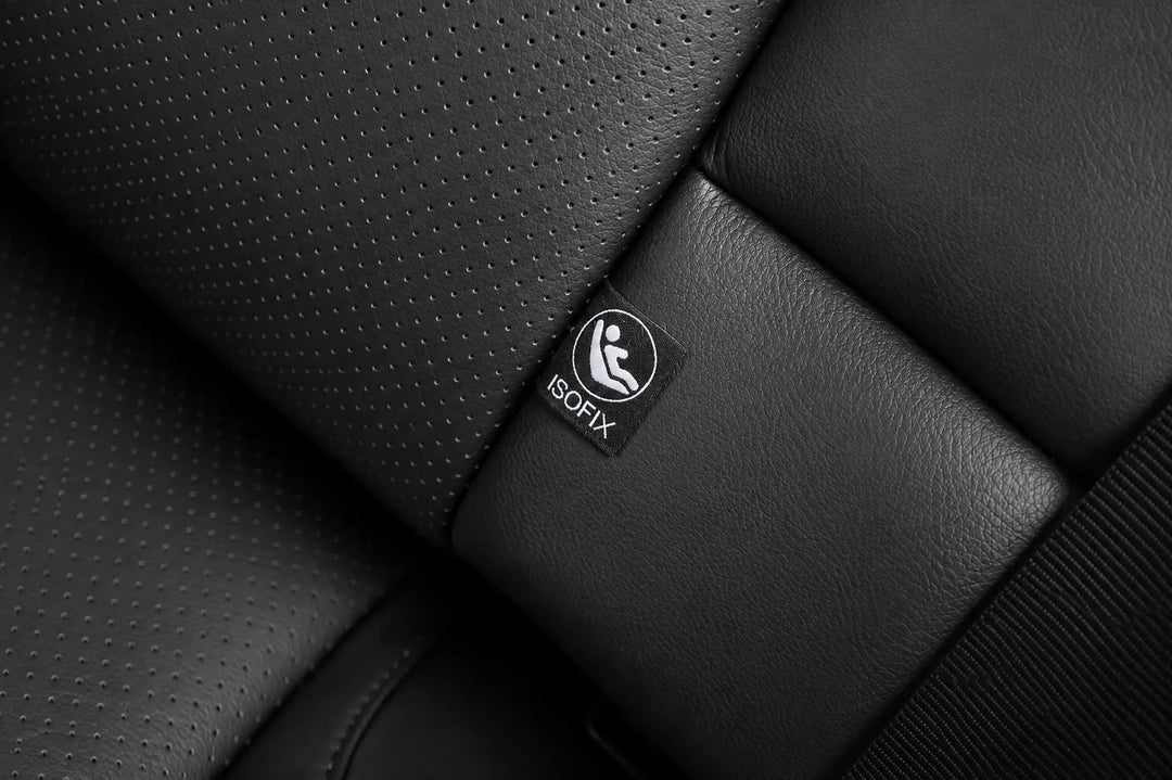 Close-up of a black car seat with perforated and smooth leather-like panels, featuring a small visible ISOFIX label on the seat.