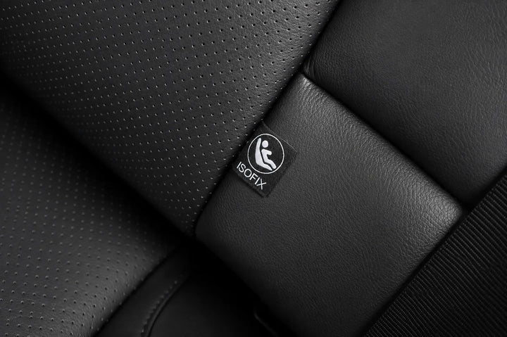 Close-up of a black car seat with perforated and smooth leather-like panels, featuring a small visible ISOFIX label on the seat.