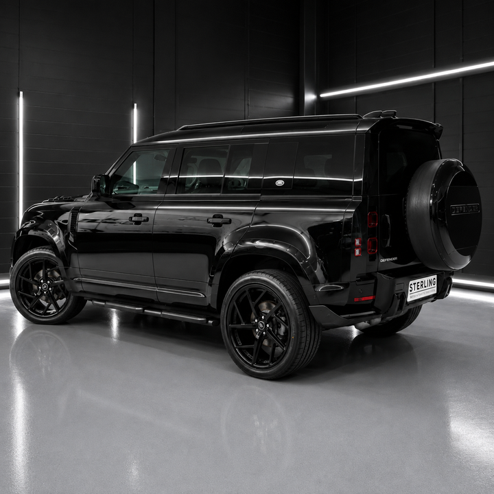 A glossy black SUV shown from a rear three-quarter angle in a dark studio setting with linear LED lighting and a reflective floor.