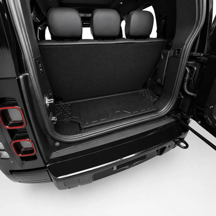 A black rubber cargo liner installed in the open trunk of a black vehicle, showing the liner on the floor and sides of the cargo area.