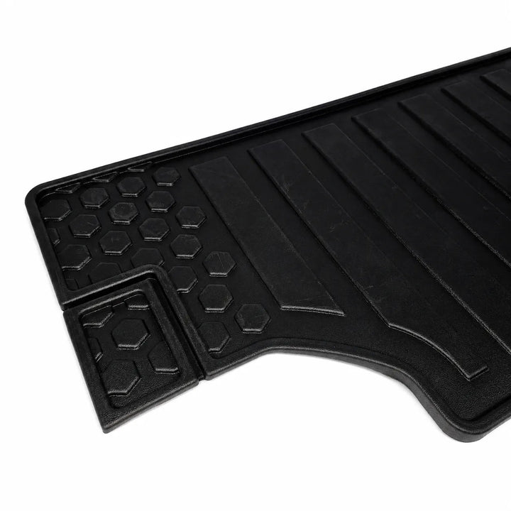 A black rubber car floor mat with a textured honeycomb pattern and raised channel grooves, shown on a plain white background.