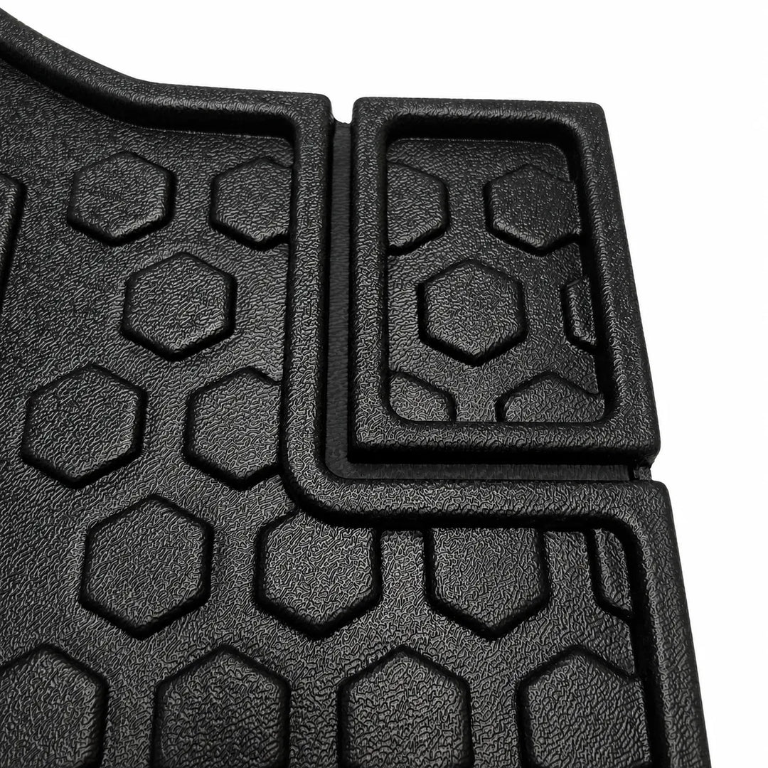 Close-up of a black textured rubber floor mat with a raised hexagonal tread pattern and a rectangular section with a recessed hexagonal design, shown on a white background.