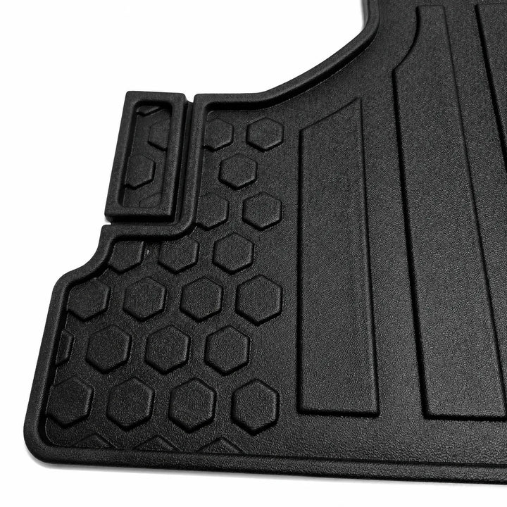 A close-up of a black molded rubber or plastic floor mat with textured honeycomb and ribbed sections, photographed on a white background.