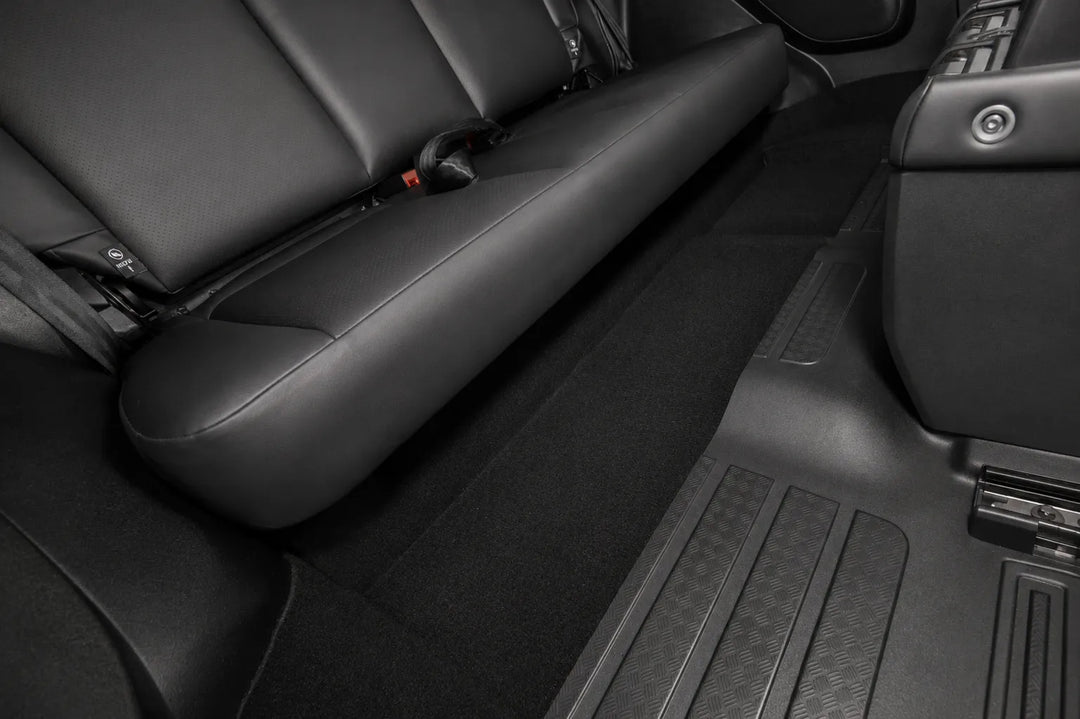 Black leather car interior showing the rear seat, floor carpet, and center console area.