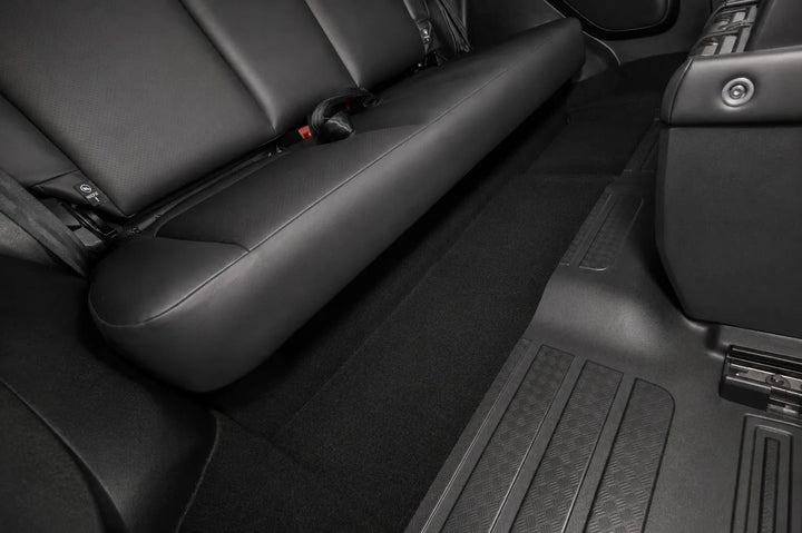 Black leather car interior showing the rear seat, floor carpet, and center console area.