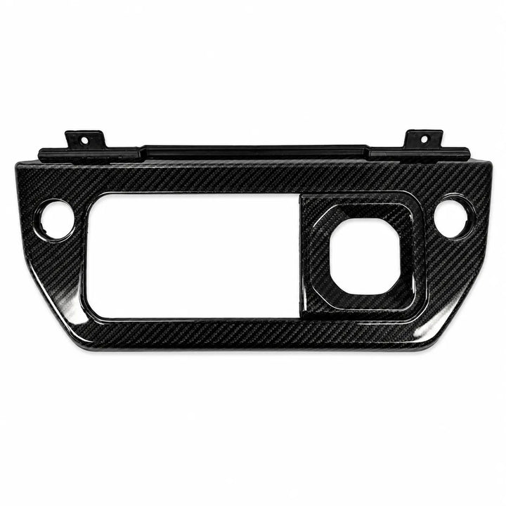 A glossy black carbon fiber trim piece with a textured weave pattern, featuring pre-drilled mounting holes and cutouts for a dashboard or console panel.