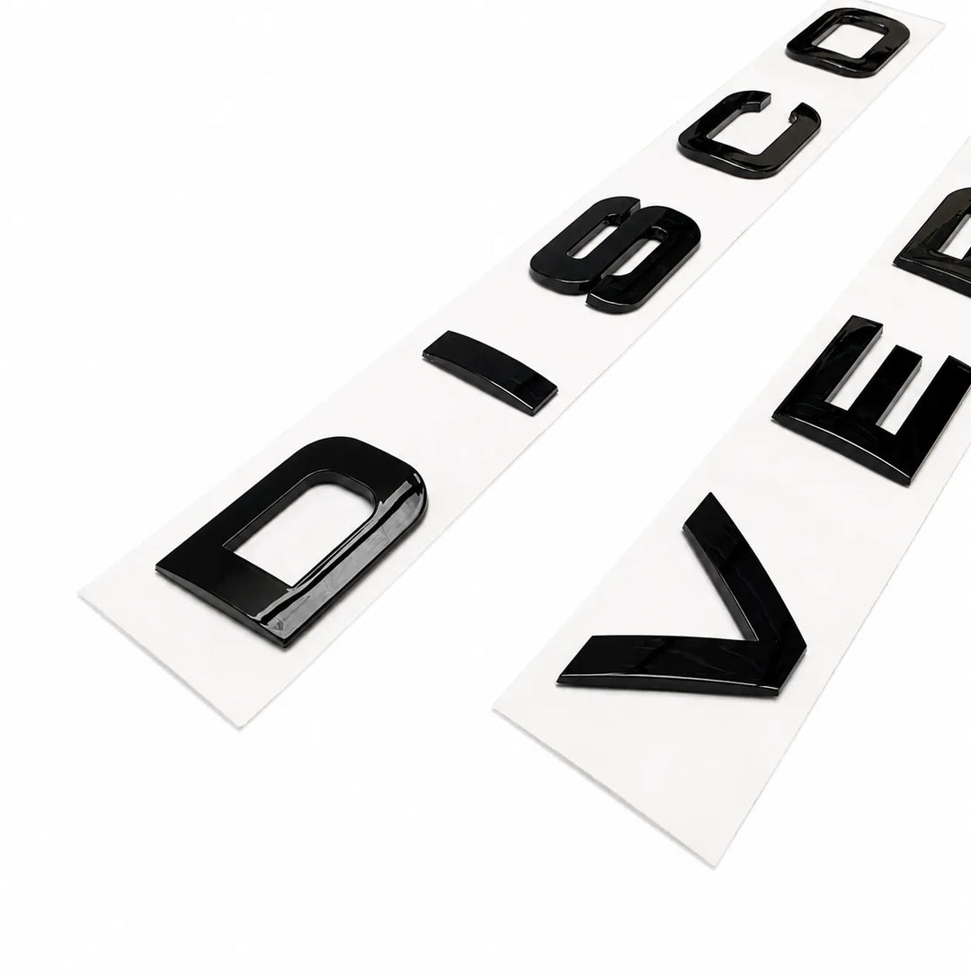 Two strips of glossy black raised letter decals on white backing sheets, photographed on a clean white background.