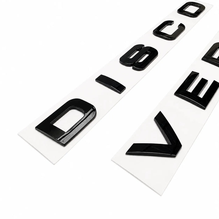 Two strips of glossy black raised letter decals on white backing sheets, photographed on a clean white background.