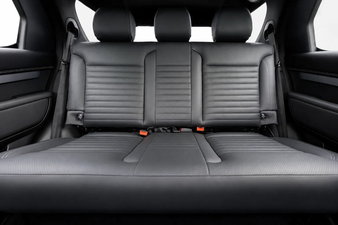 Rear bench seat in a vehicle interior, upholstered in dark gray leather with horizontal stitching and center console armrests visible on both sides.