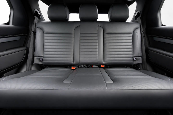 Rear bench seat in a vehicle interior, upholstered in dark gray leather with horizontal stitching and center console armrests visible on both sides.