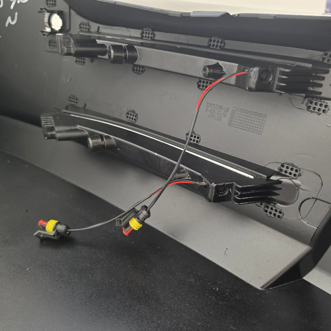 Close-up of the interior rear panel of a black appliance, showing metal mounting hardware, vent holes, and wiring with red and black cables and yellow connector caps.