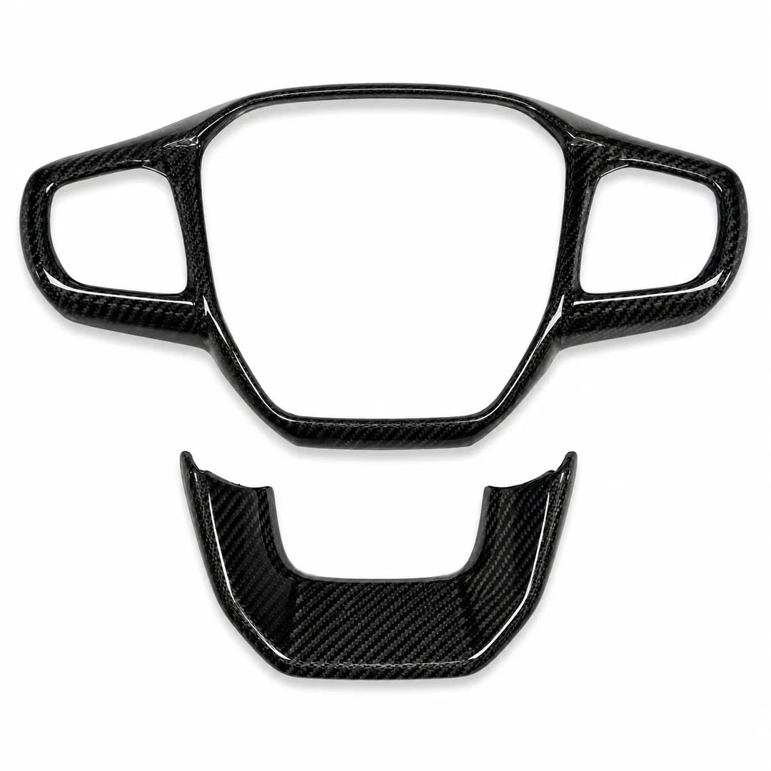 A pair of glossy black carbon fiber steering wheel trim pieces, including a large center console surround and a smaller lower accent piece, displayed on a clean white background.