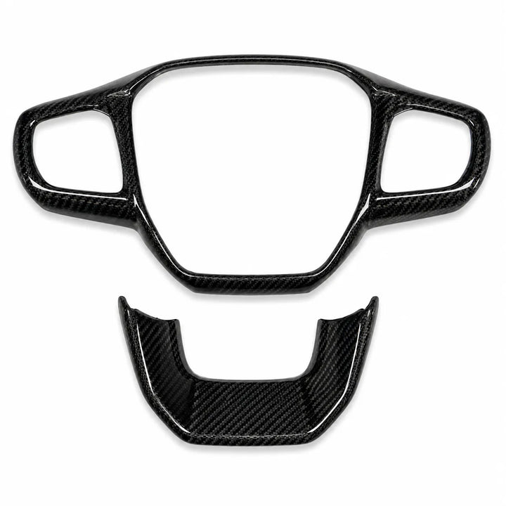 A pair of glossy black carbon fiber steering wheel trim pieces, including a large center console surround and a smaller lower accent piece, displayed on a clean white background.