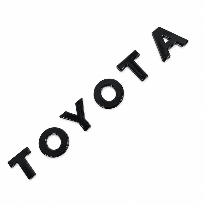 Black glossy vinyl lettering spelling 'TOYOTA' arranged diagonally on a plain white background.