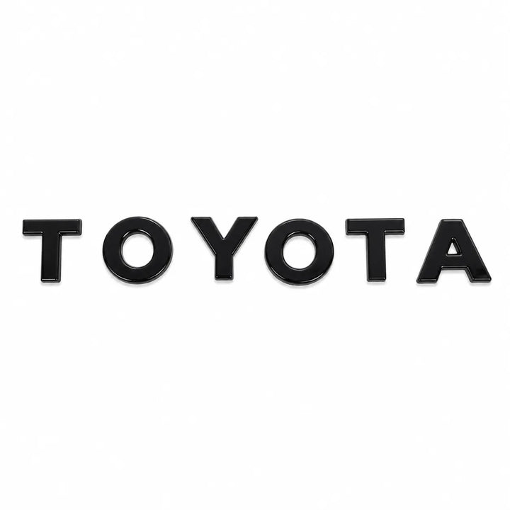Black glossy 3D Plastic Toyota lettering arranged on a plain white background.