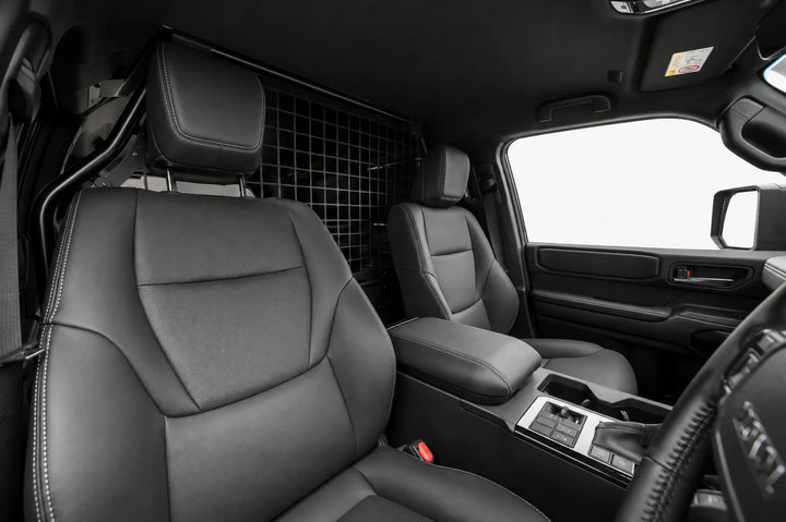 Front Seats passenger area of a Land Cruiser Toyota LC250 SUV, showing the front seats before the conversion and a rear mesh bulk head partition between the cargo area and the seats.